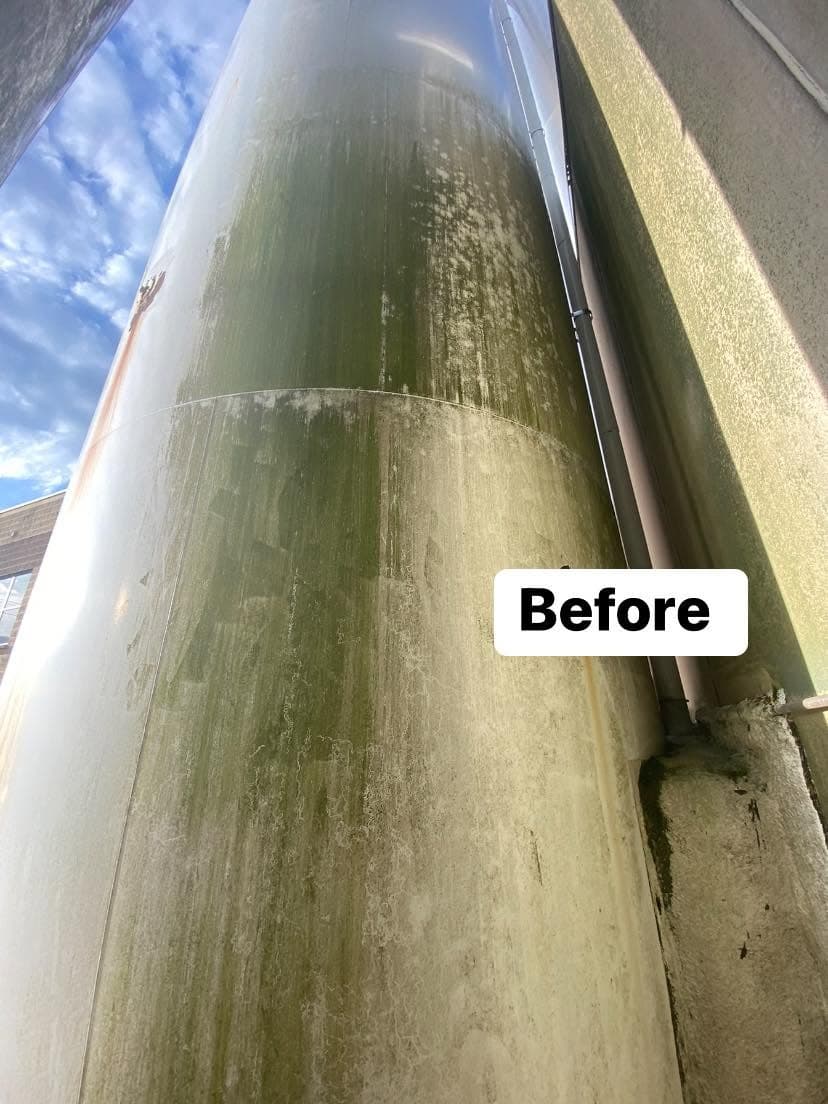 Before cleaning: close-up of algae-covered cylindrical structure against blue sky.