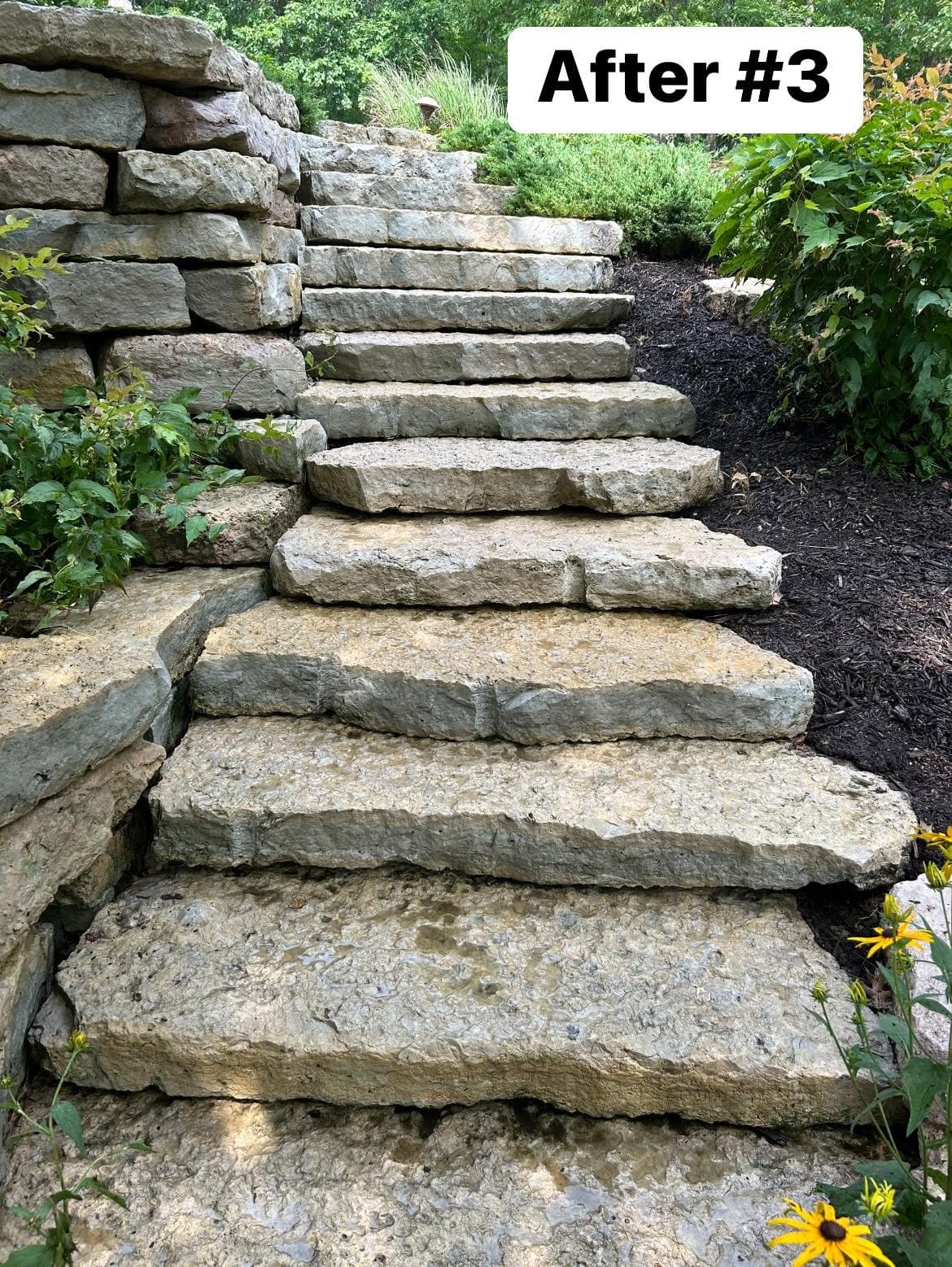 Stone steps lead up a landscaped garden, showcasing natural rock design and greenery.