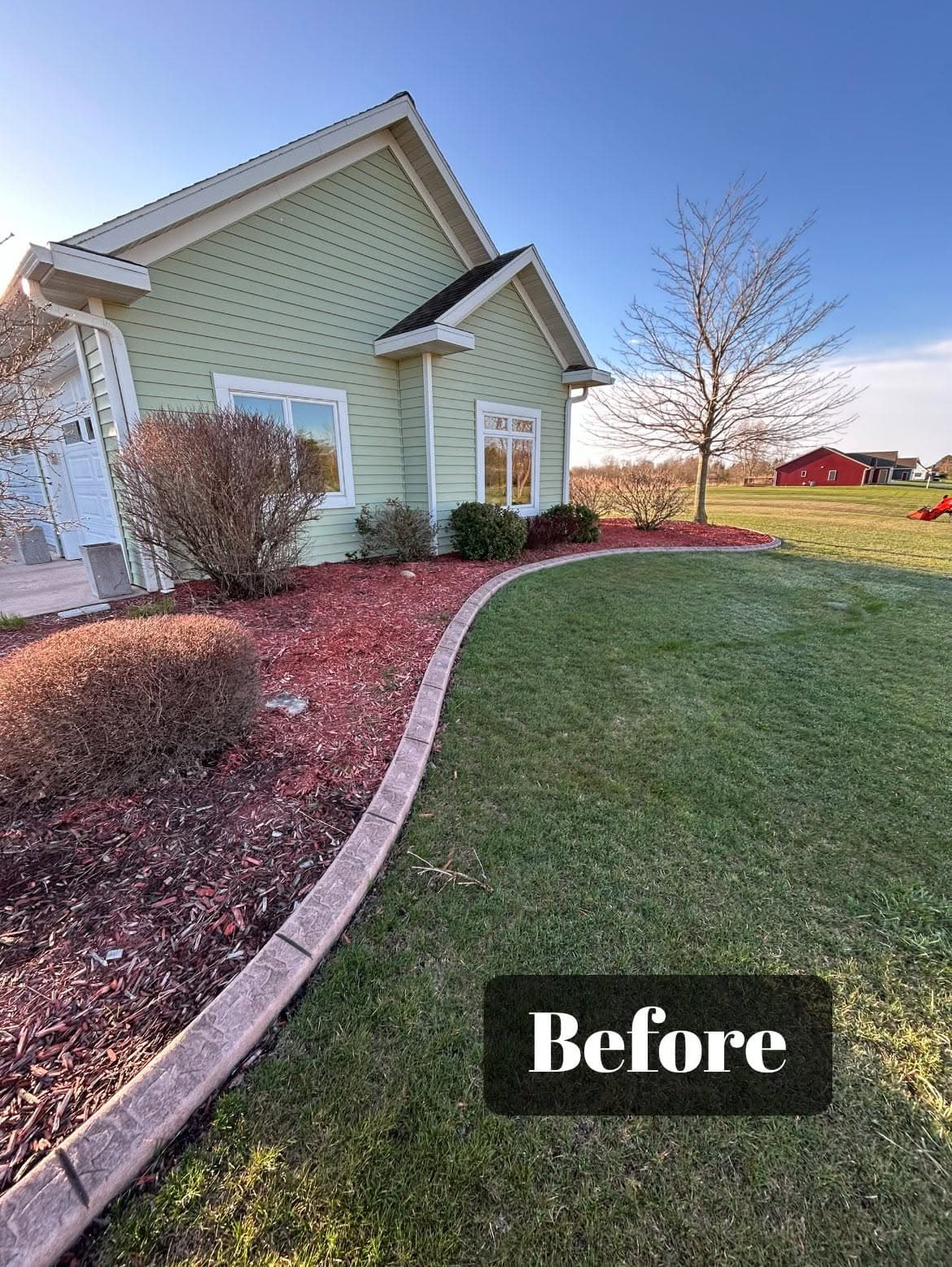Before image of a well-maintained house exterior with landscaped yard and colorful mulch.