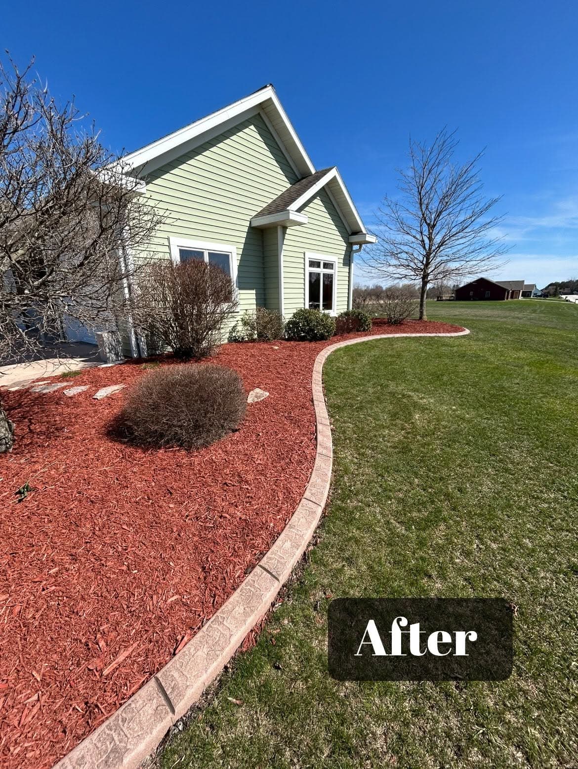 After landscaping transformation with fresh mulch and manicured lawn around a home.