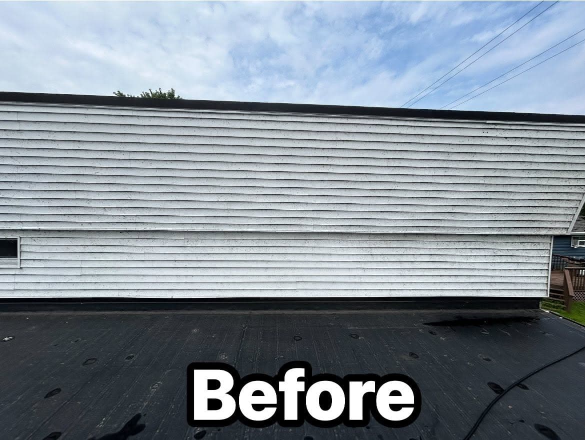 Before photo of a weathered white siding on a house, with a clear blue sky overhead.