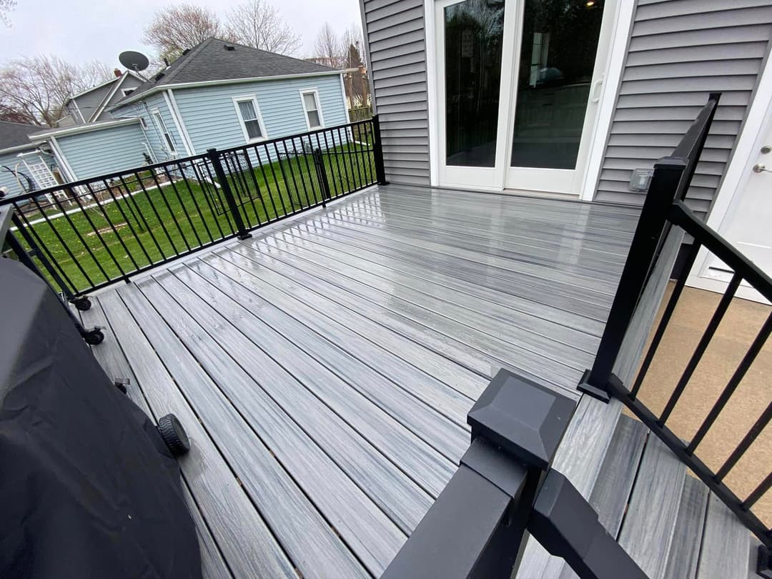 Modern composite deck with grey stripes, black railing, and outdoor grill area.